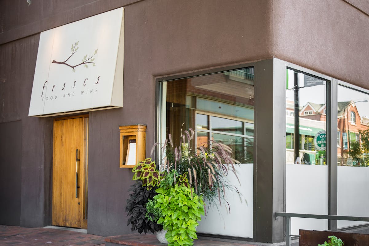 front of the restaurant with a big window and plants